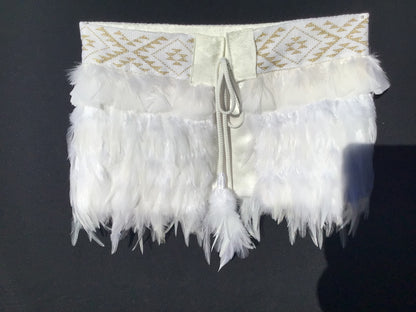 White feathered item with gold embroidery on a dark background